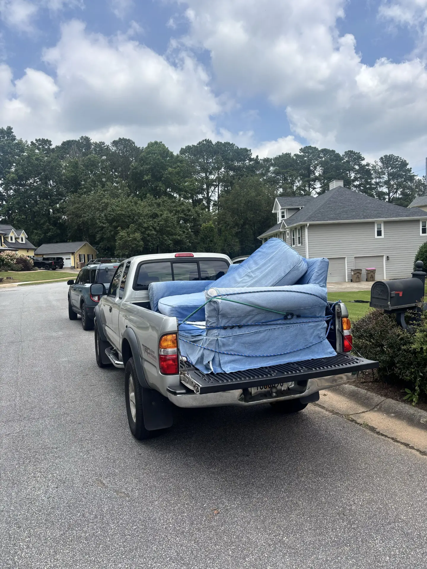 Bad Boys Junk Removal truck bed loaded with a mattress and furniture in a North Atlanta neighborhood