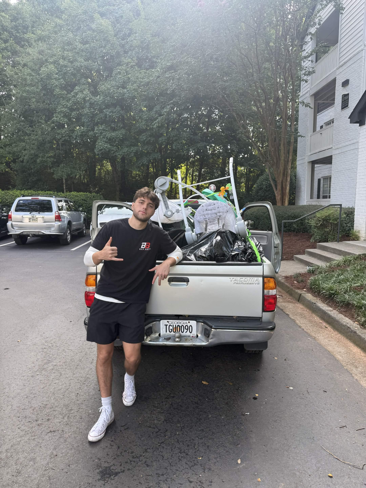 Bad Boys Junk Removal crew member beside a Tacoma loaded with a stroller, baby gear and bagged household junk in an Alpharetta apartment community