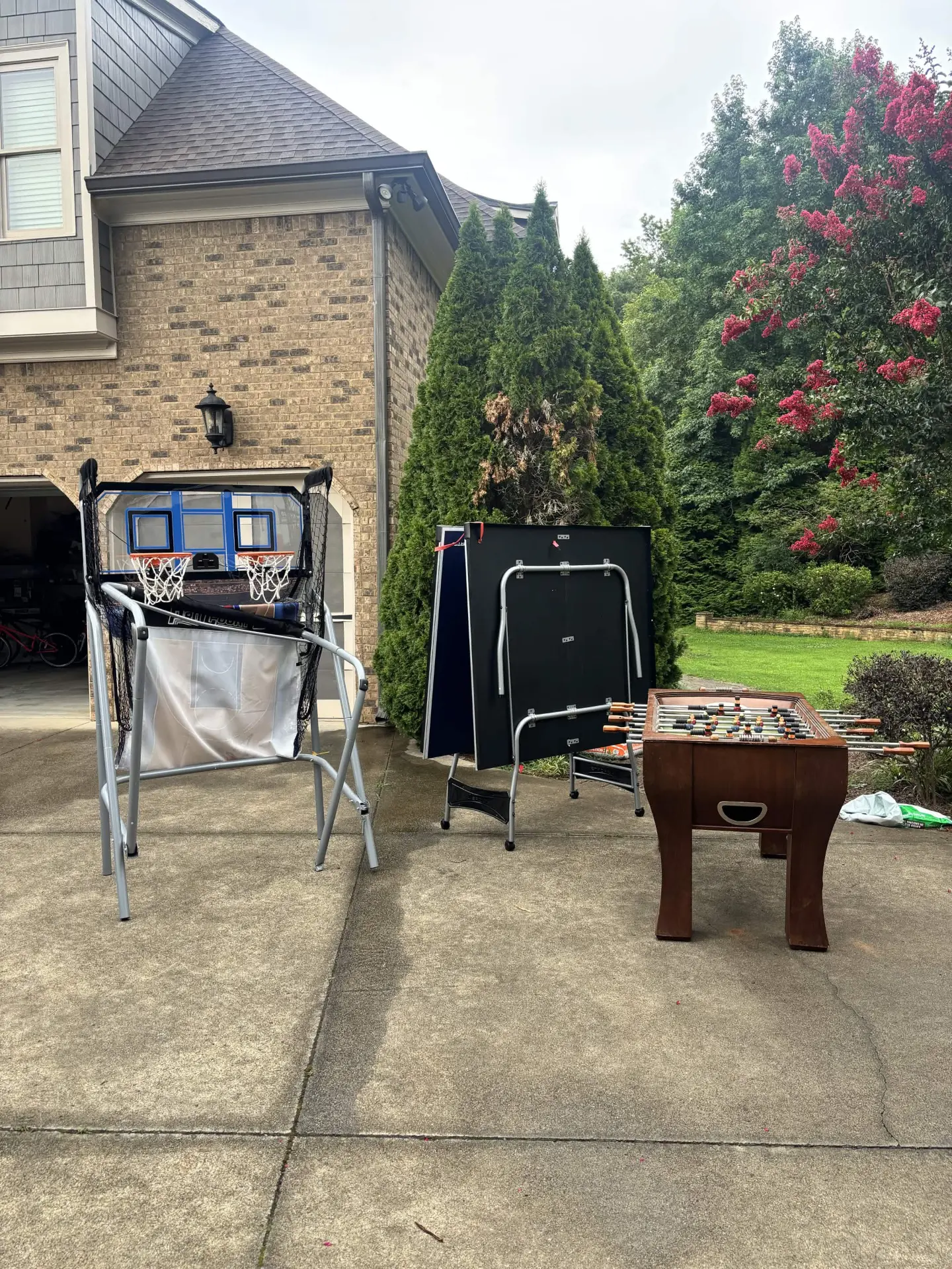 Arcade basketball, ping-pong and foosball games ready for household junk removal in a driveway