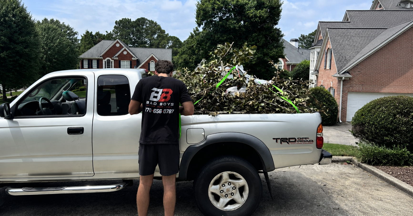 Bad Boys Junk Removal truck loaded with branches and yard debris in a North Atlanta driveway