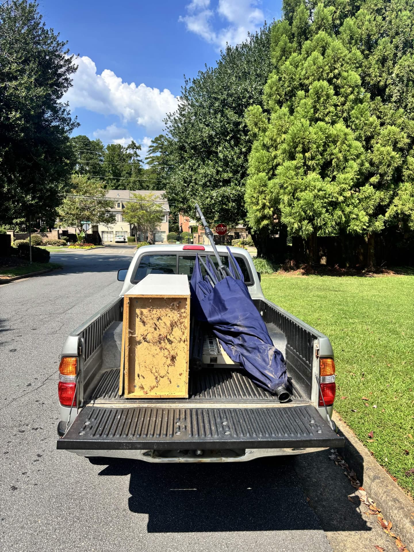 Bad Boys Junk Removal truck loaded with a cabinet, patio umbrella, and other items from a Roswell, GA junk removal job